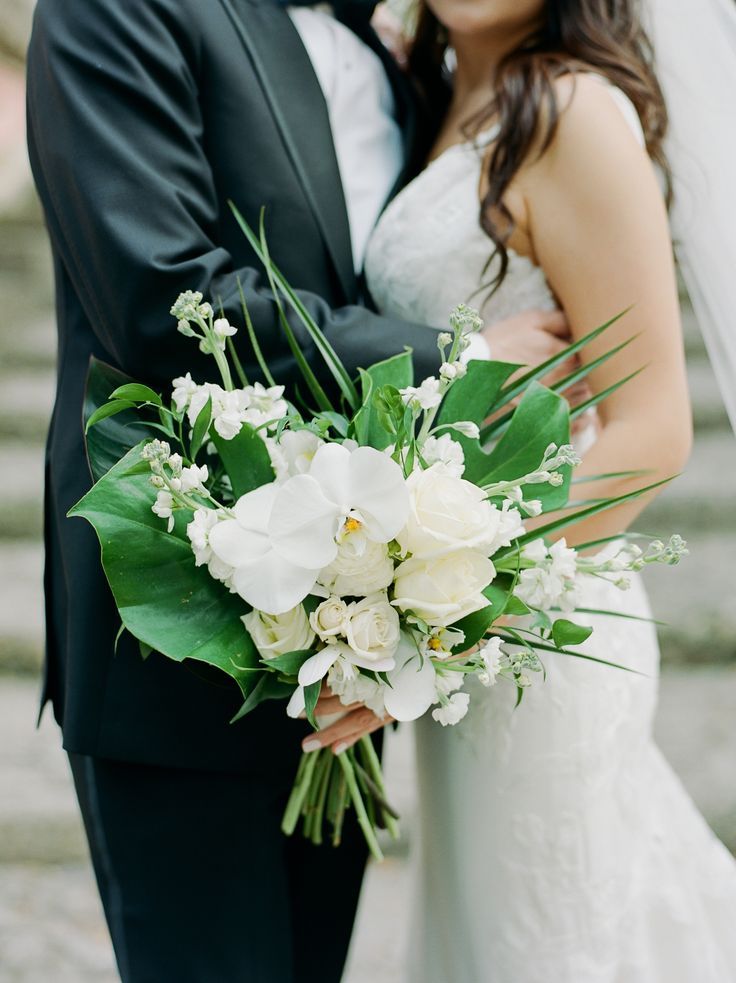 the bride and groom are posing for a wedding photo on some steps with their bouquet in hand