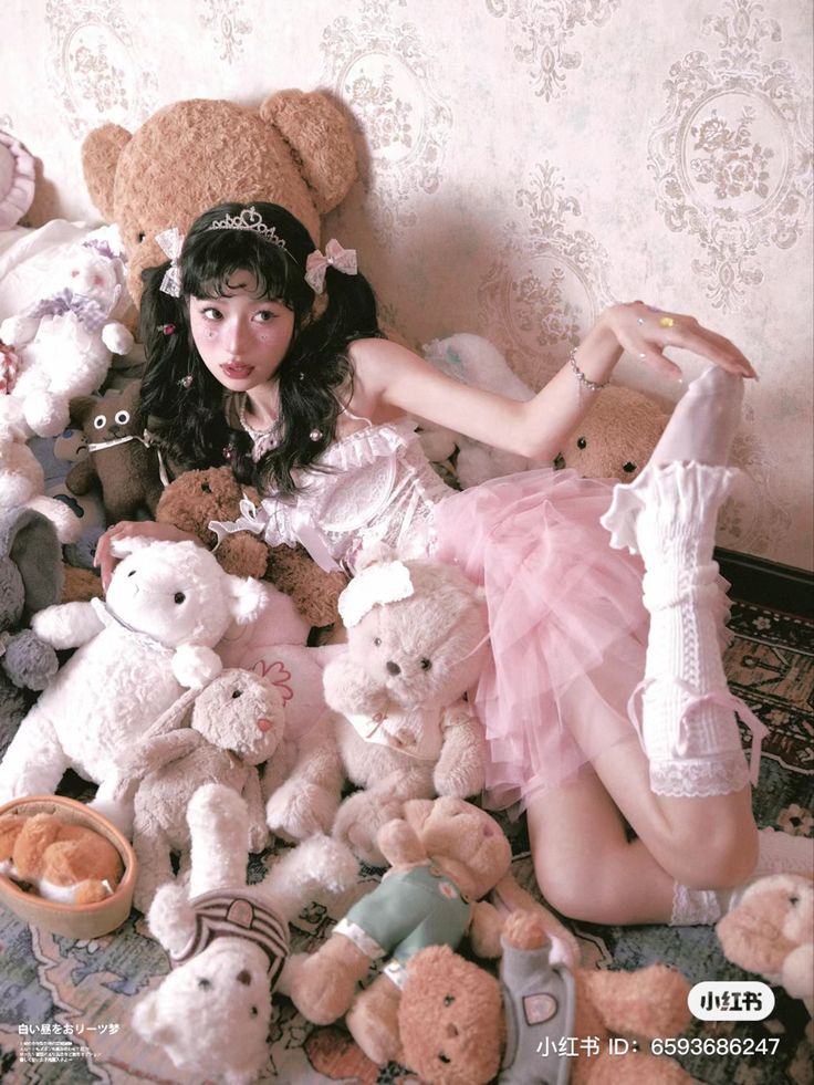 a woman sitting on the floor surrounded by teddy bears and other stuffed animals, posing for a photo