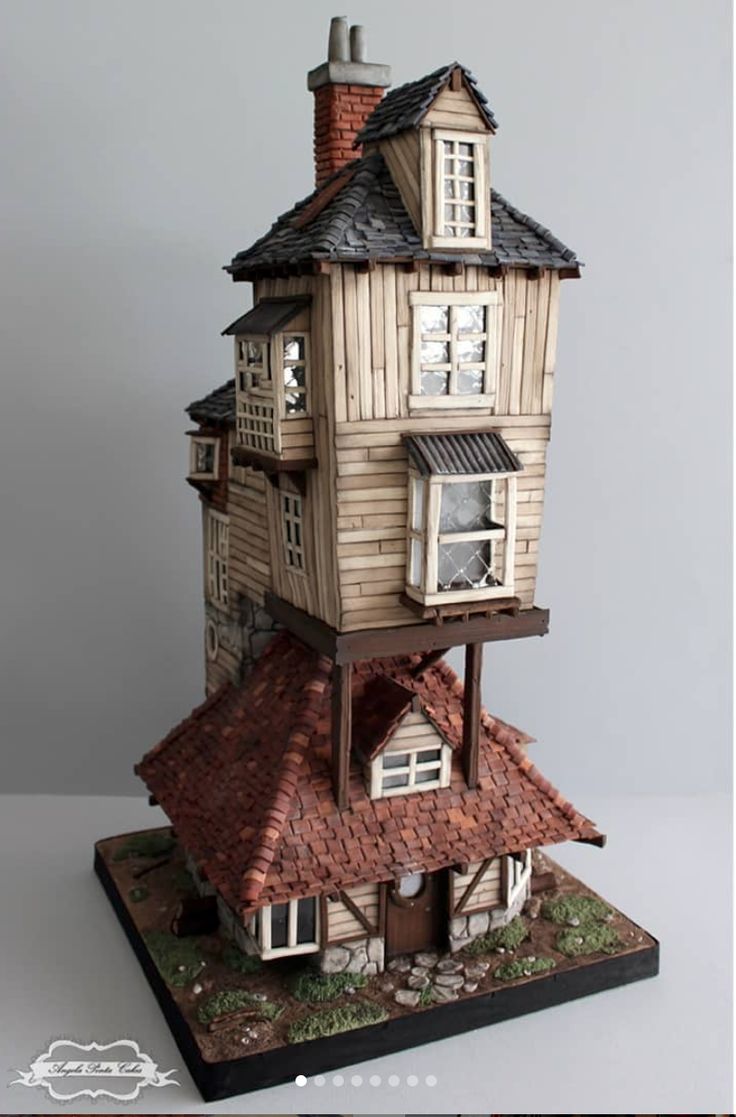 a tall wooden house sitting on top of a table next to a window and roof