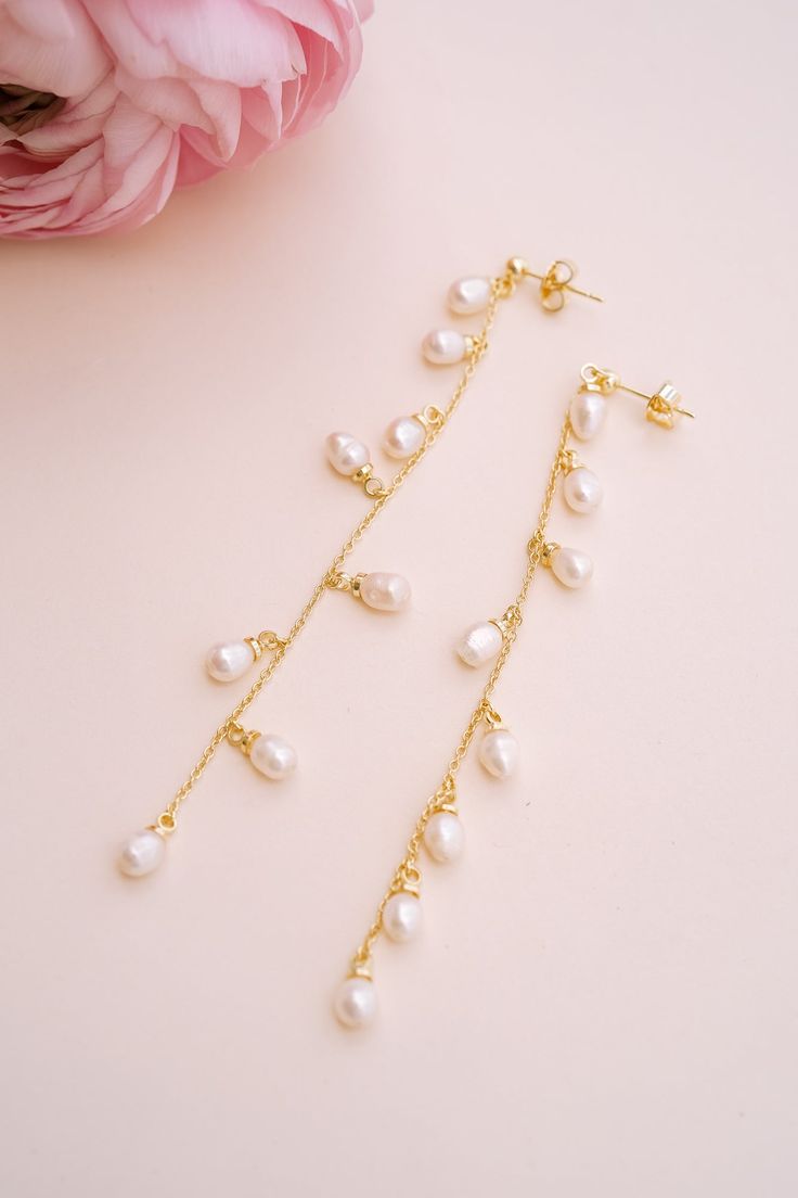 Add a touch of graceful elegance to your bridal look with the Whispering Pearl Drop Earrings! These stunning dangle earrings feature freshwater pearls delicately hanging from a fine gold chain, creating a perfect balance of timeless beauty and modern sophistication. Why do we love them? They’re the perfect blend of chic and classic beauty, making them a must-have for your special day! EARRING FEATURES Material: Brass, Freshwater Pearls Dimensions/Size: 3.2" drop Finish: Polished 14k Gold Plating Elegant Pearl Charm Chandelier Dangle Earrings, Elegant Pearl Charm Chandelier Earrings, Elegant Drop Pearl Earrings With Dangling Beads, Elegant Pearl Chandelier Earrings With Dangling Beads, Elegant Pearl Earrings With Dangling Beads For Gift, Elegant White 14k Gold Filled Bridal Earrings, Yellow Gold Pearl Drop Dangle Chandelier Earrings, Elegant Chandelier Earrings With Pearl Chain, Elegant Pearl Chain Chandelier Earrings As Gift