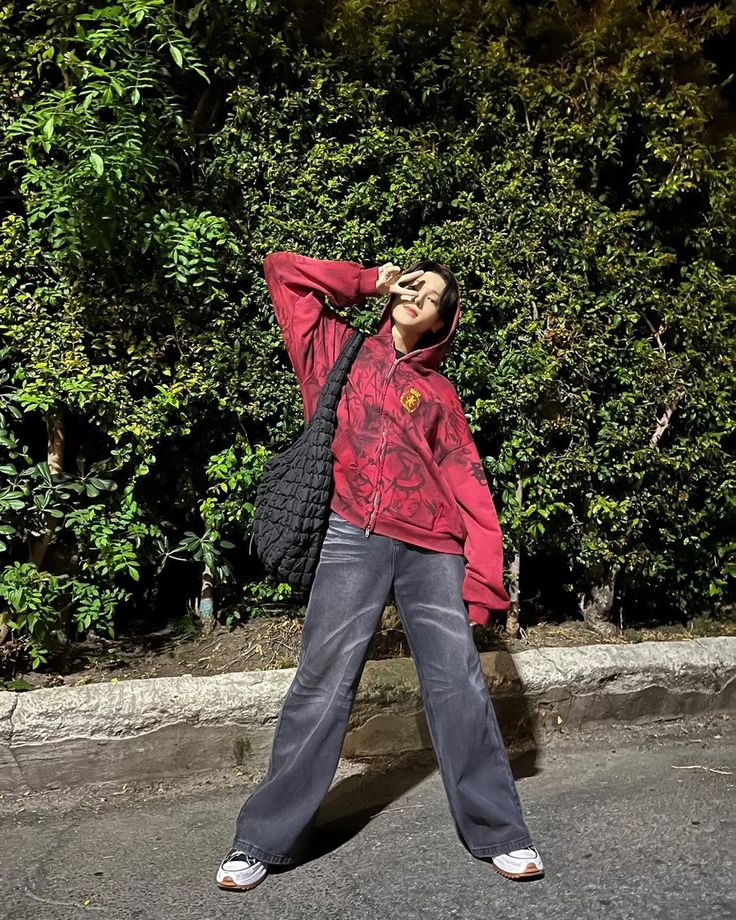 a woman standing in front of a bush with her hands on her head and eyes closed