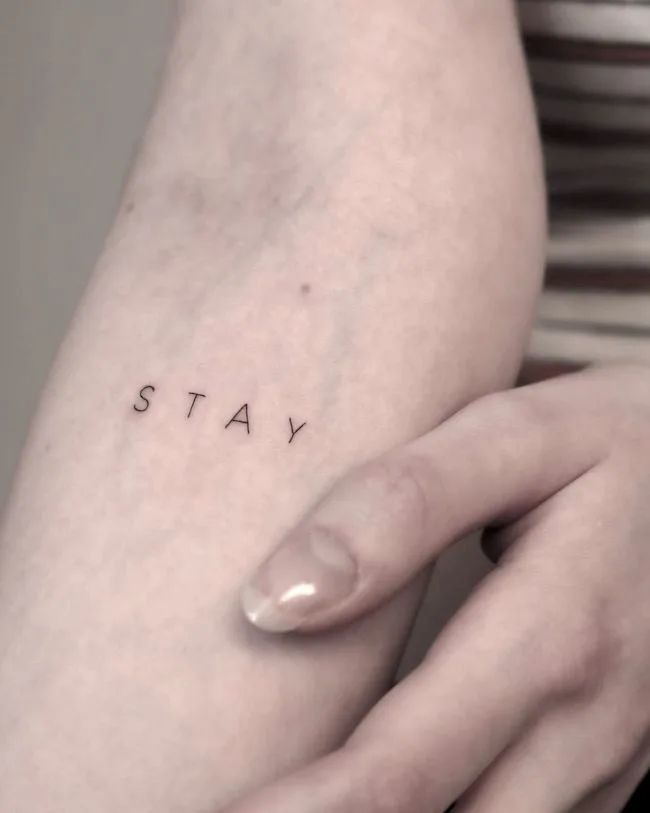 a woman's arm with the word stay tattooed on her left side, in black ink