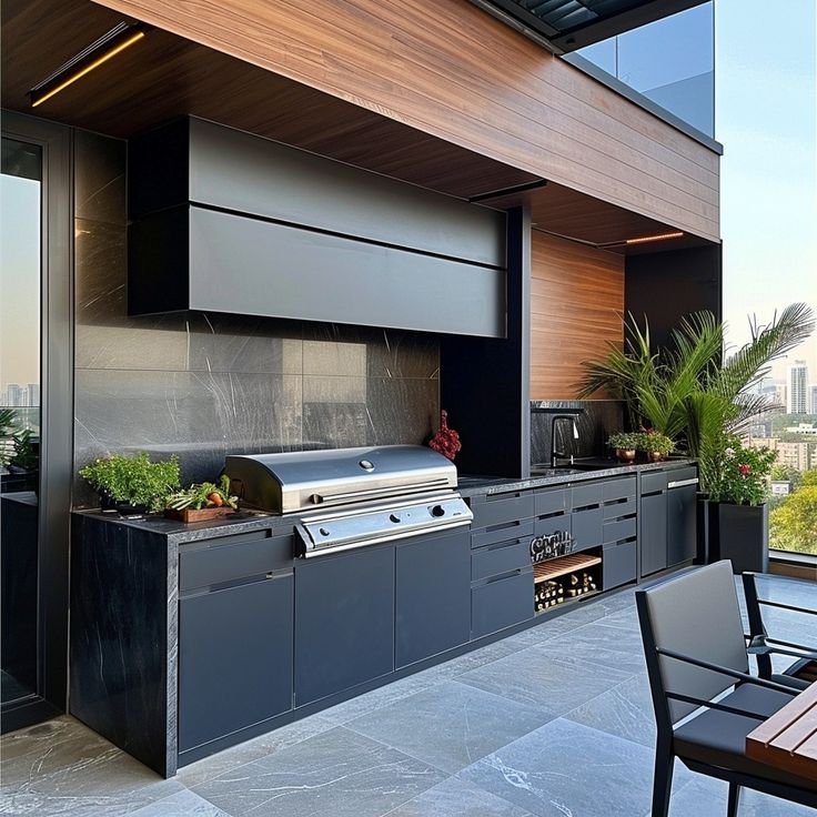 an outdoor kitchen with grill, table and chairs