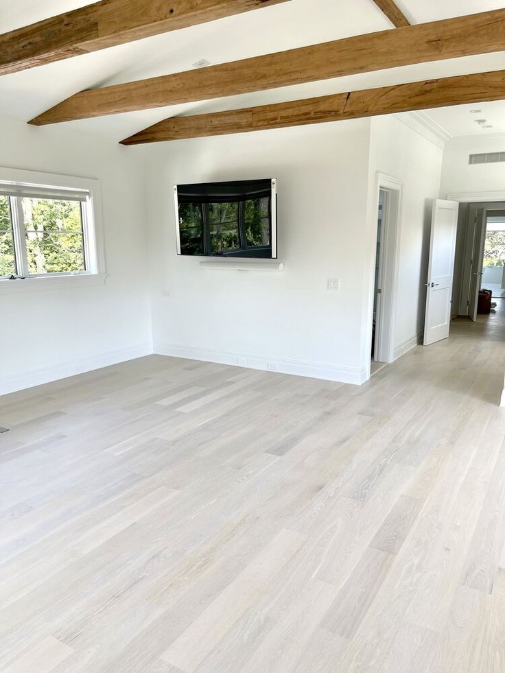 an empty living room with white walls and wood flooring is seen in this image