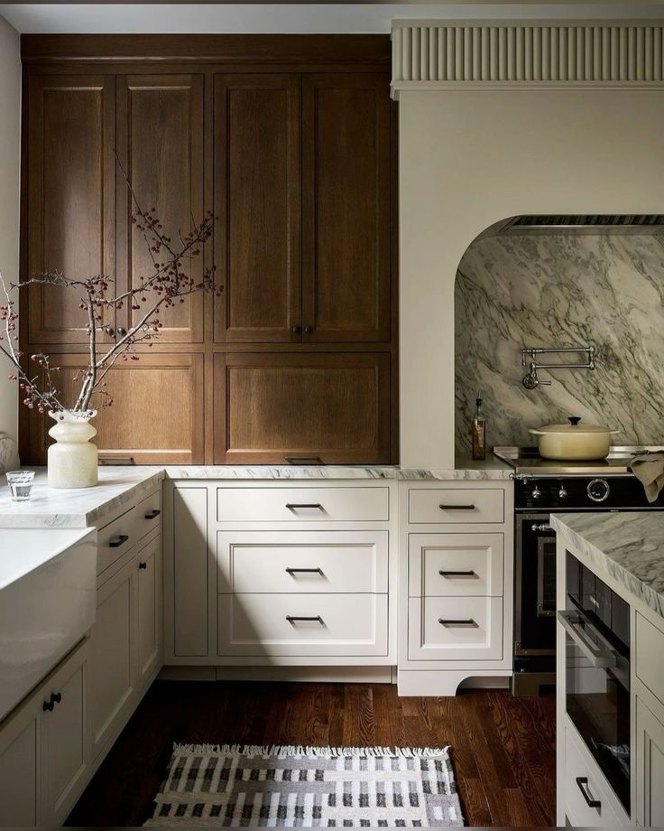 a kitchen with white cabinets and marble counter tops, wood flooring, and wooden cabinetry