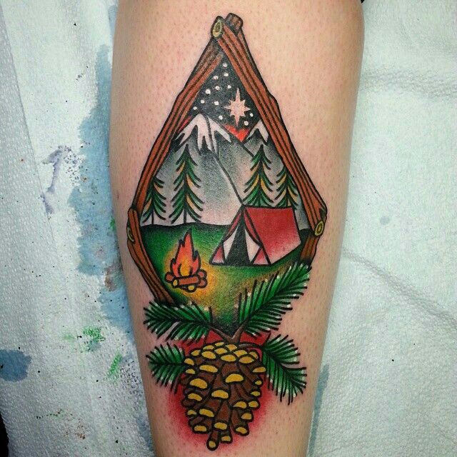 a tattoo with a tent, pine cones and campfire in the woods on someone's leg