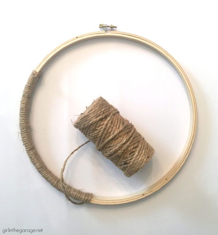 a round wooden frame with some twine on it and a piece of wood in the middle