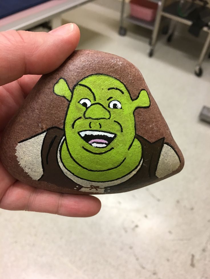 a hand holding a rock with a cartoon character painted on it