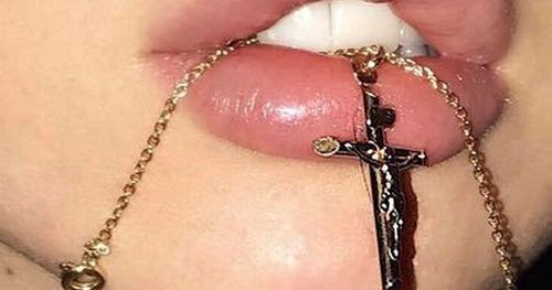 a close up of a person with a cross on it's lip and chain around their mouth