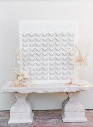 a white table topped with flowers on top of a stone bench next to a wall