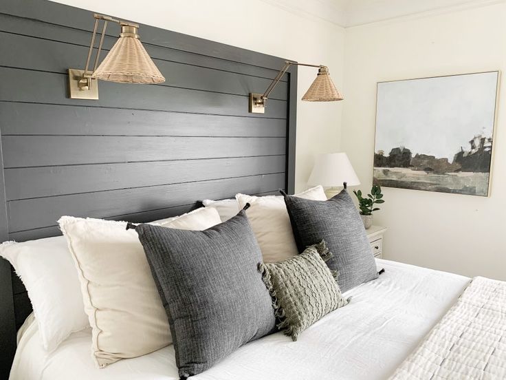 a bed with white sheets and gray pillows