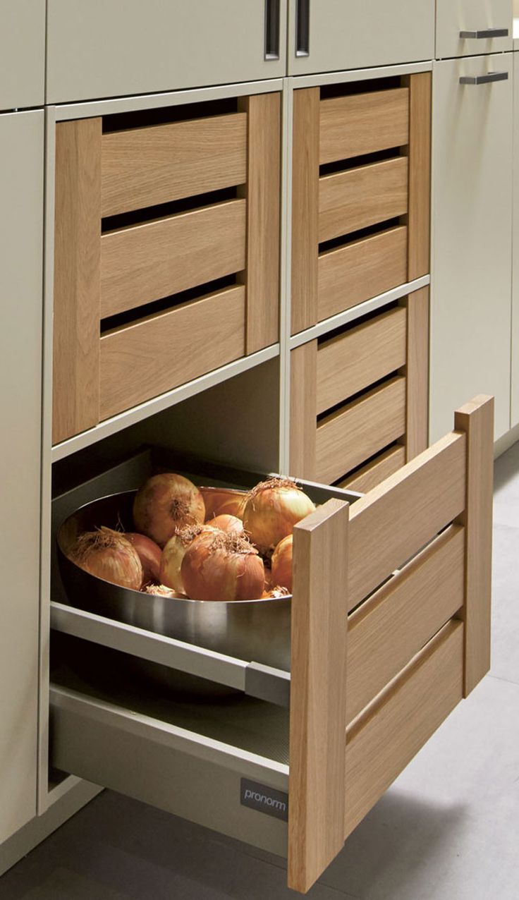 an open drawer in a kitchen with some food on the bottom shelf and cabinets behind it