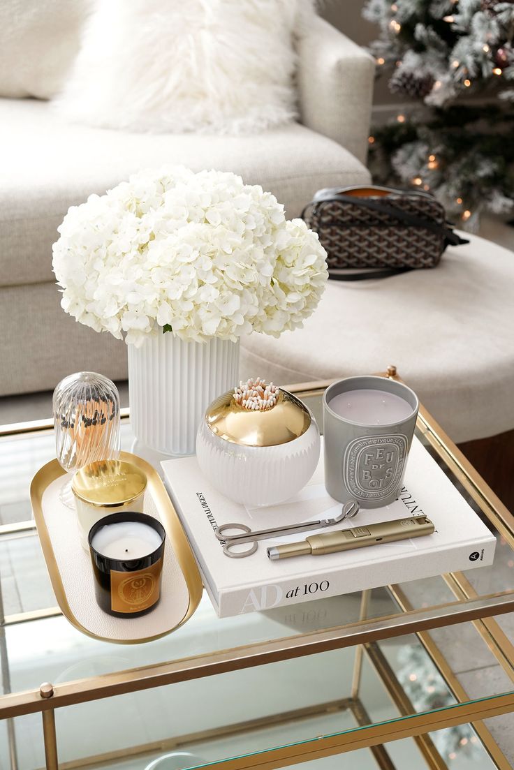 a coffee table with white flowers in a vase and other items on the trays