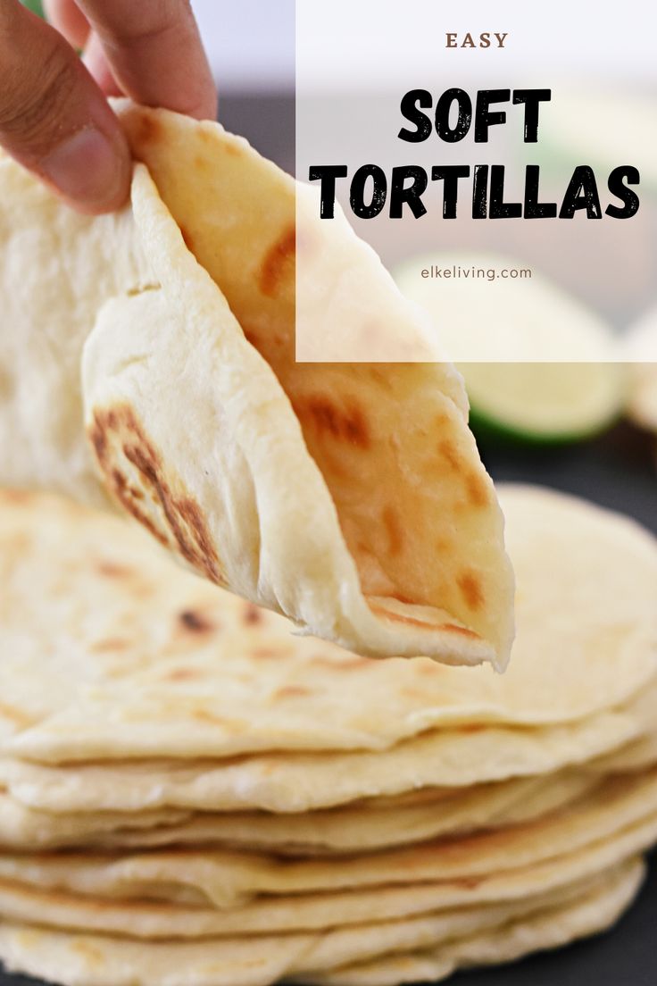 a hand holding a tortilla over a stack of flatbreads on a plate