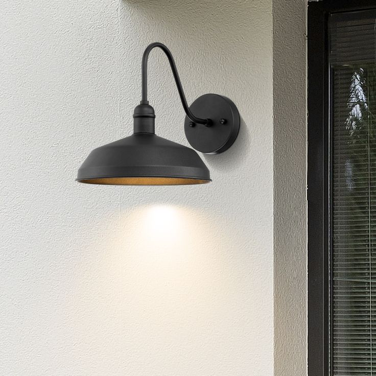 an outdoor light mounted on the side of a wall next to a window with blinds