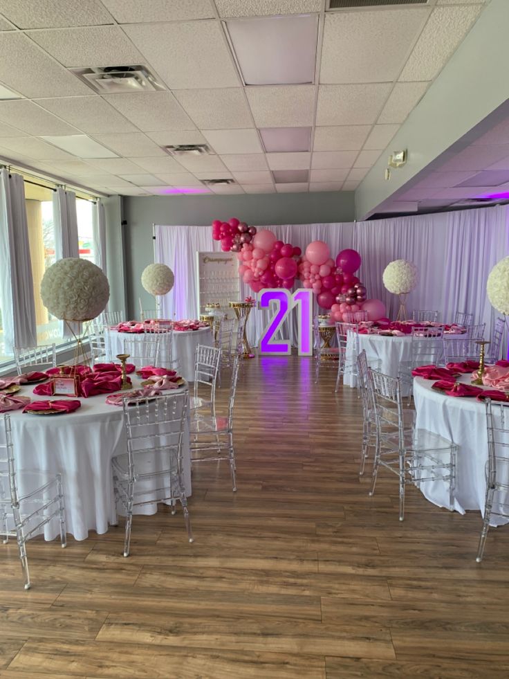 tables and chairs are set up for an event with pink, white and silver decorations