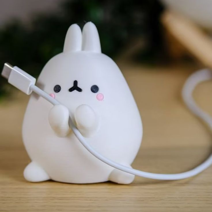 a little white bunny holding a charger plugged in