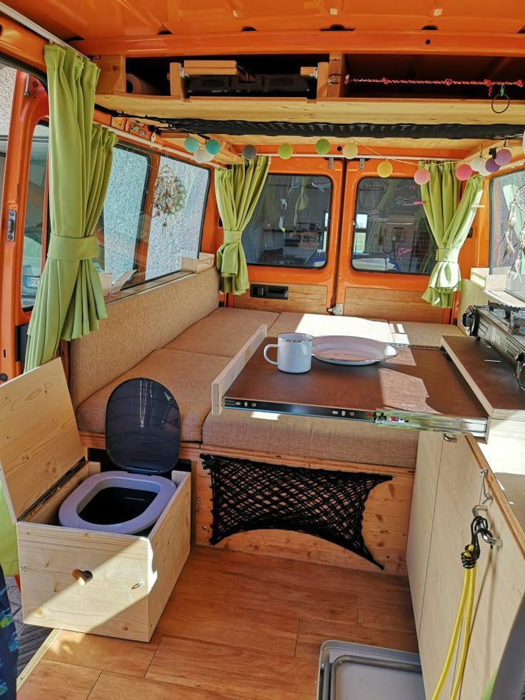 the interior of an orange van with green drapes on it's windows and wood flooring