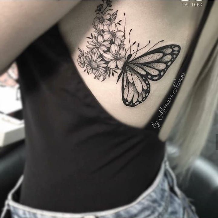 a woman's back with a butterfly and flowers tattoo on her left side ribcage