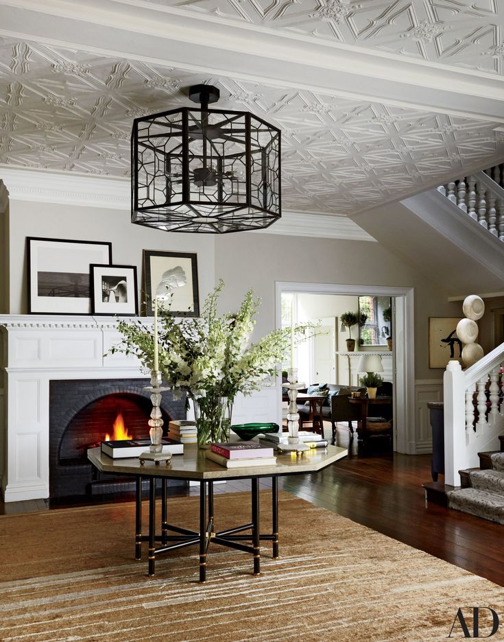 a living room filled with furniture and a fire place under a chandelier on top of a hard wood floor