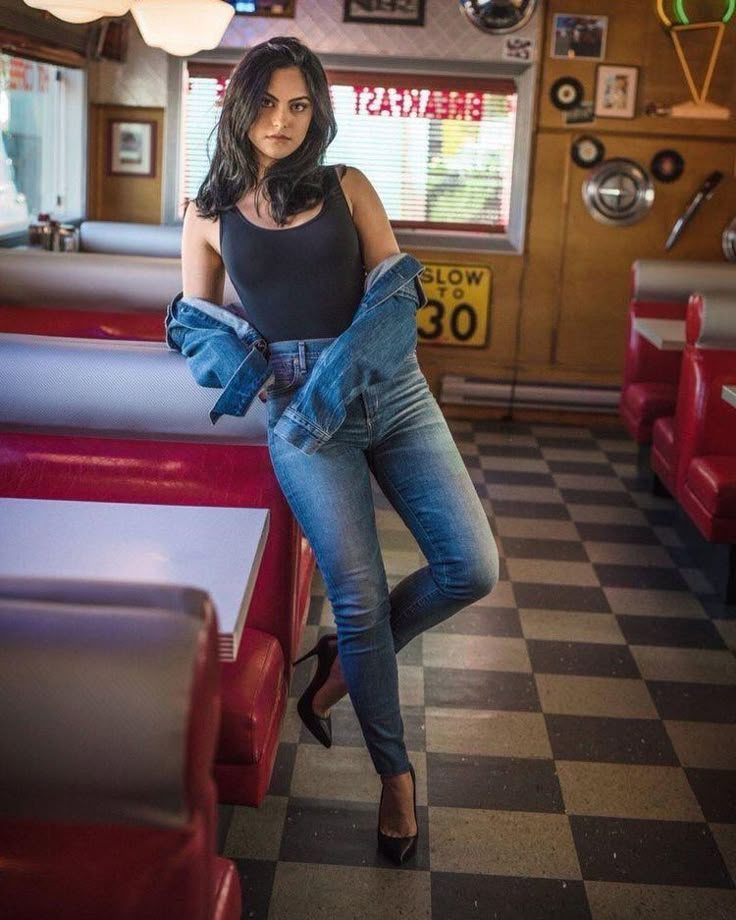 a woman standing in a diner wearing jeans and heels