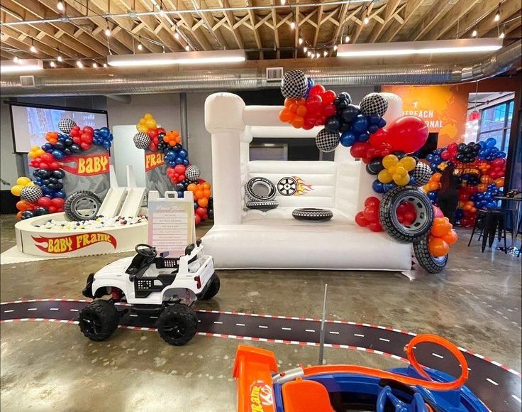 an inflatable race track with cars and balloons on the ceiling is set up for a birthday party