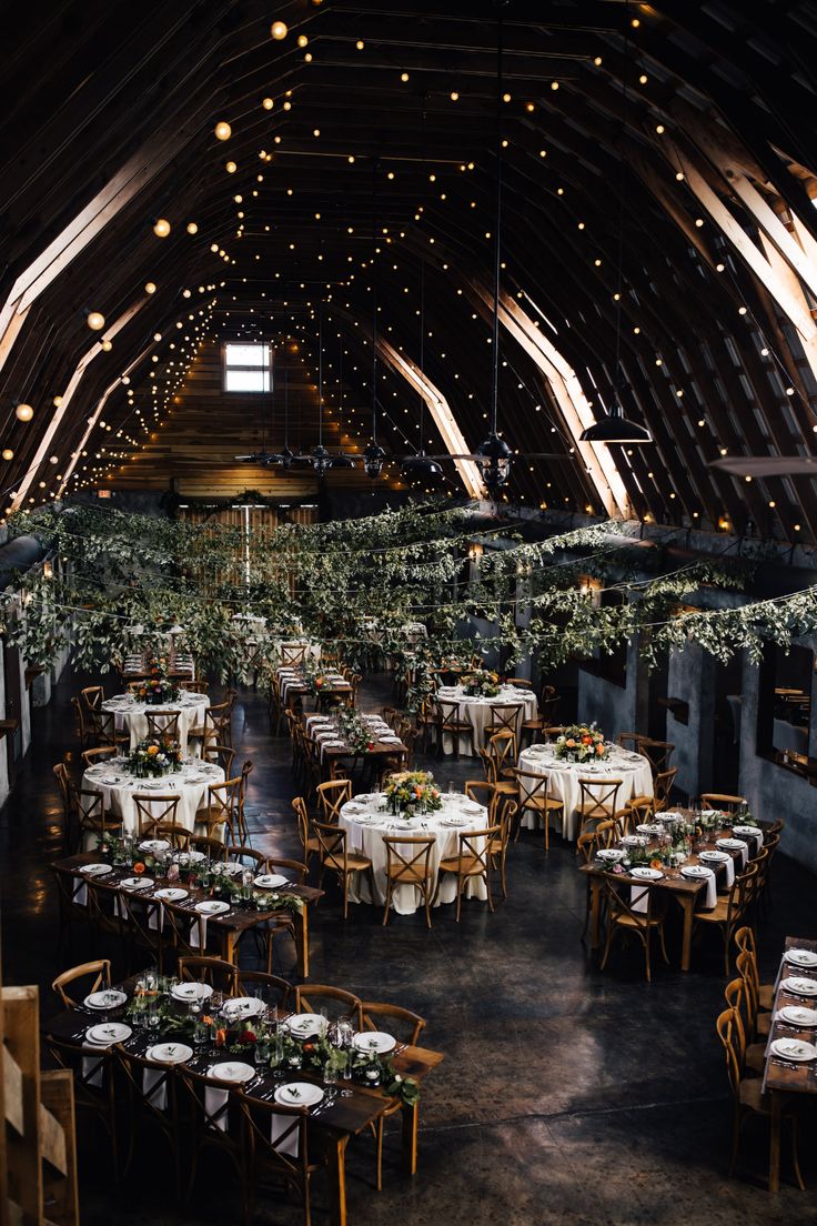 the inside of a barn with tables and chairs set up for an elegant wedding reception