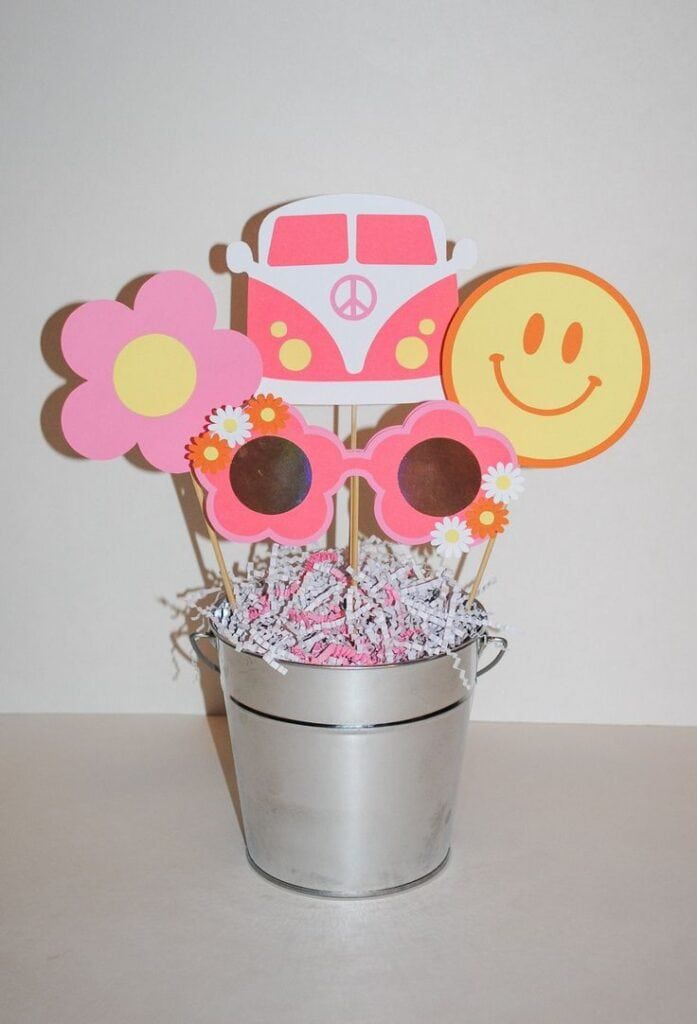 a bucket filled with flowers and paper cutouts in the shape of a car on top