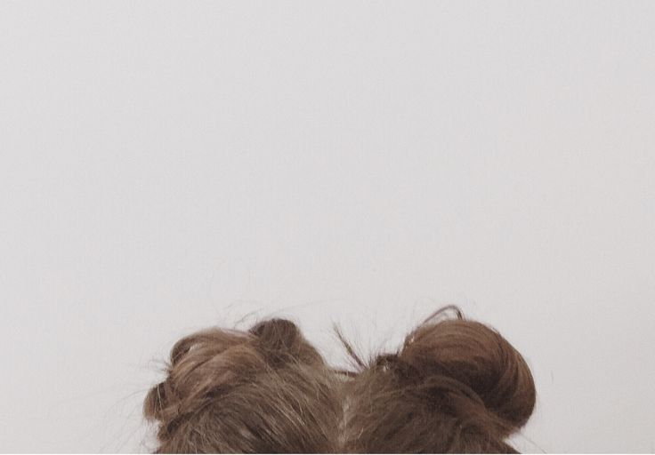 the back of a woman's head with her hair in buns looking up