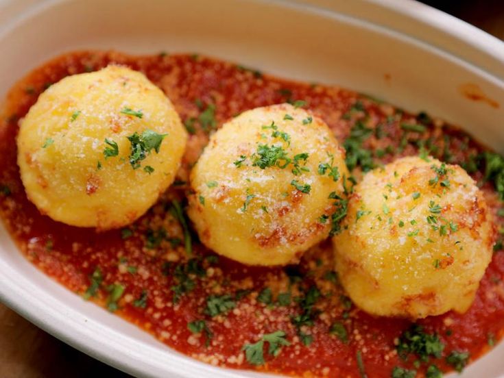 three balls of ravioli in tomato sauce with parsley sprinkled on top