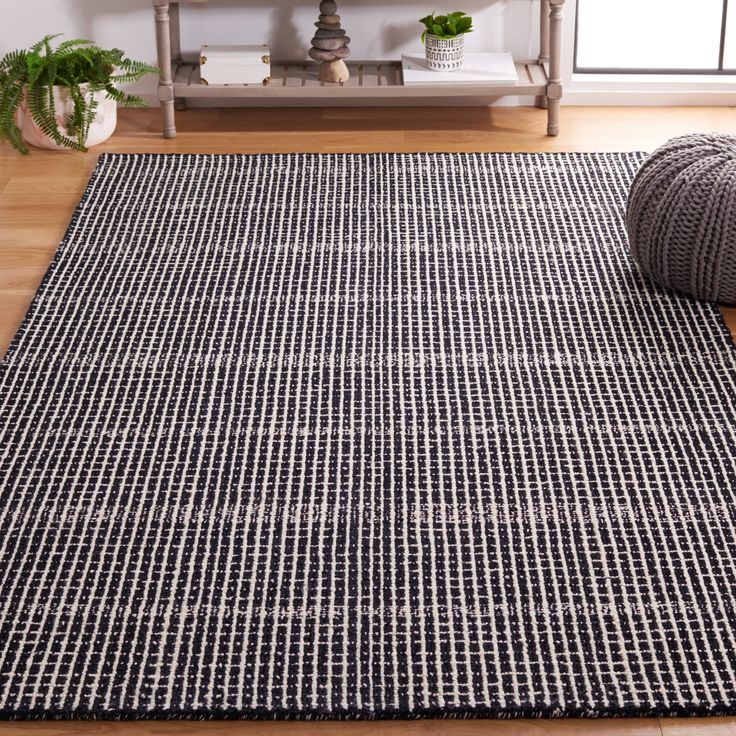 a black and white area rug on the floor in front of a shelf with potted plants