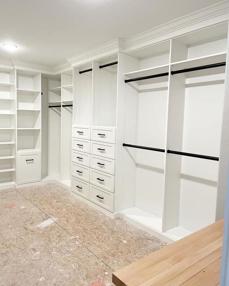 an empty walk in closet with white shelves and drawers