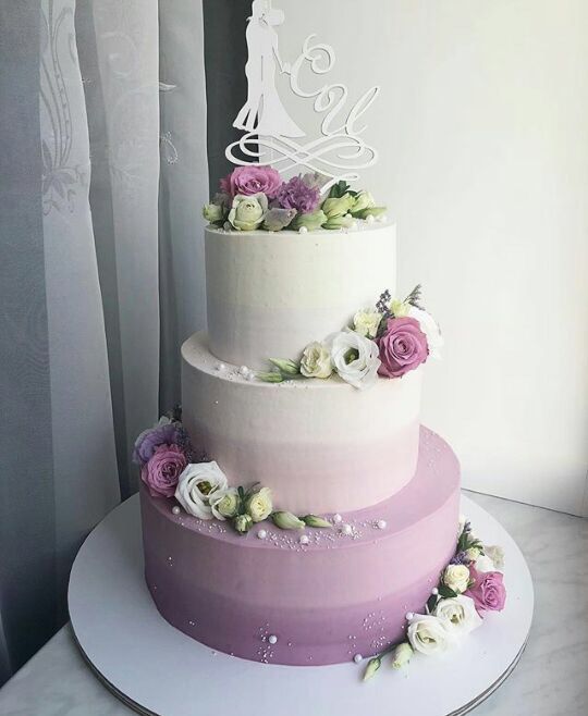 a three tiered wedding cake with flowers on the side and a bride's silhouette on top