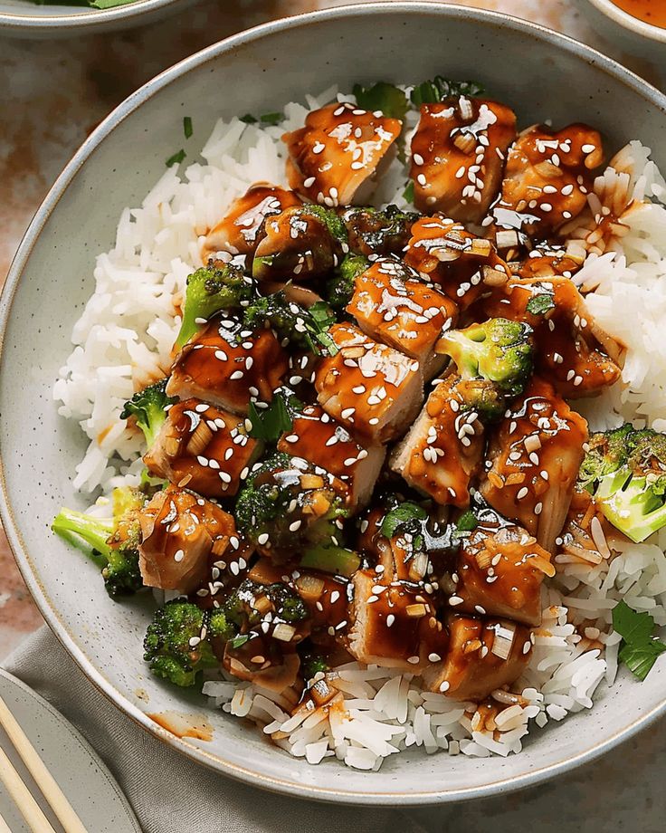 a white bowl filled with rice and broccoli covered in sesame seeds, tofu