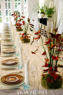 a long table is set with place settings and flowers in vases on each side