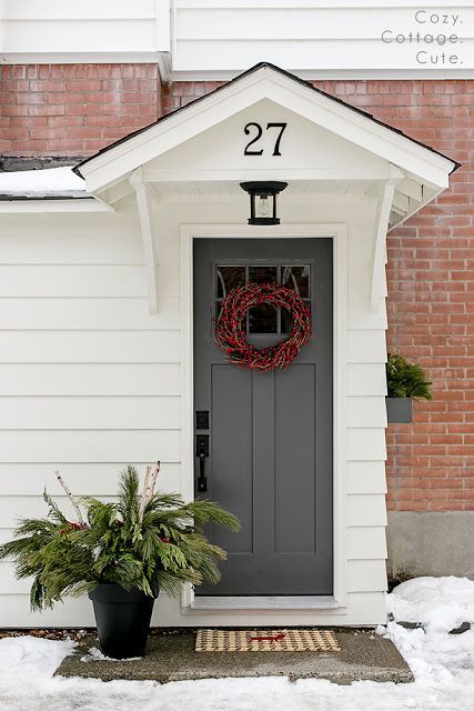 a house with a wreath on the front door and two potted plants in front