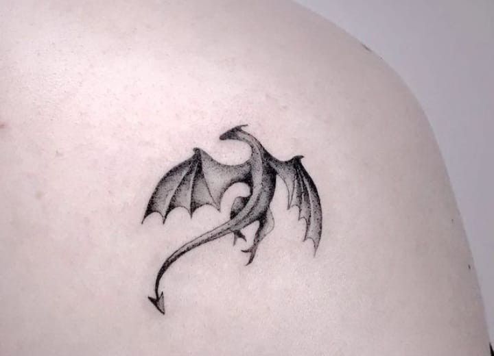 a black and white photo of a dragon tattoo on the back of a woman's shoulder