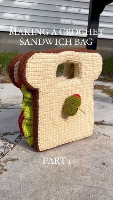 a crocheted sandwich bag sitting on top of a cement ground next to a building