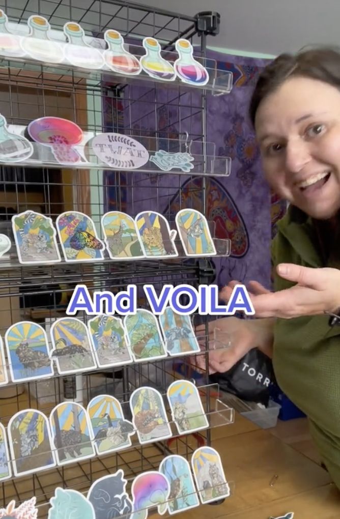 a woman is pointing at some stickers on a shelf with the words and volla in front of her