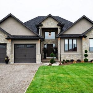 a large house with two garages on the front and side of it, surrounded by lush green grass