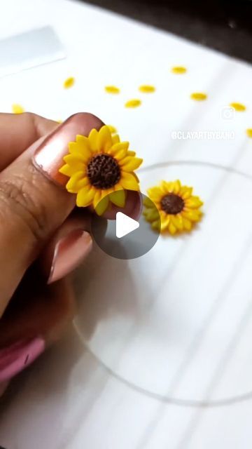 a woman's hand holding a fake sunflower on top of a piece of paper