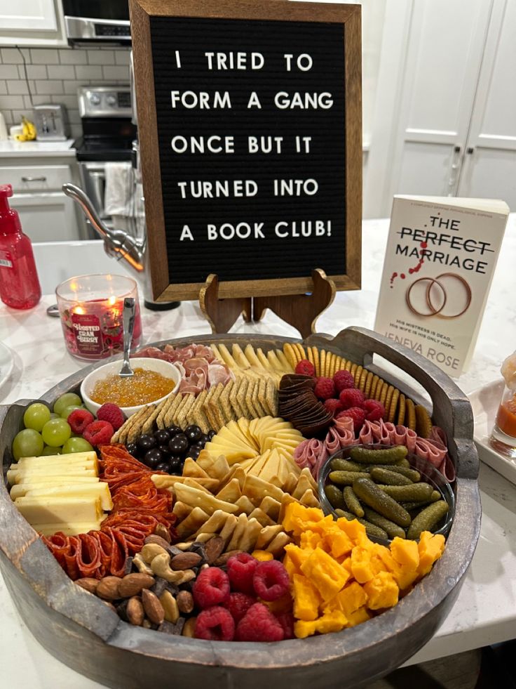 a large metal platter filled with lots of different types of food next to a sign that says i tried to form a gang once but it turned into a book club