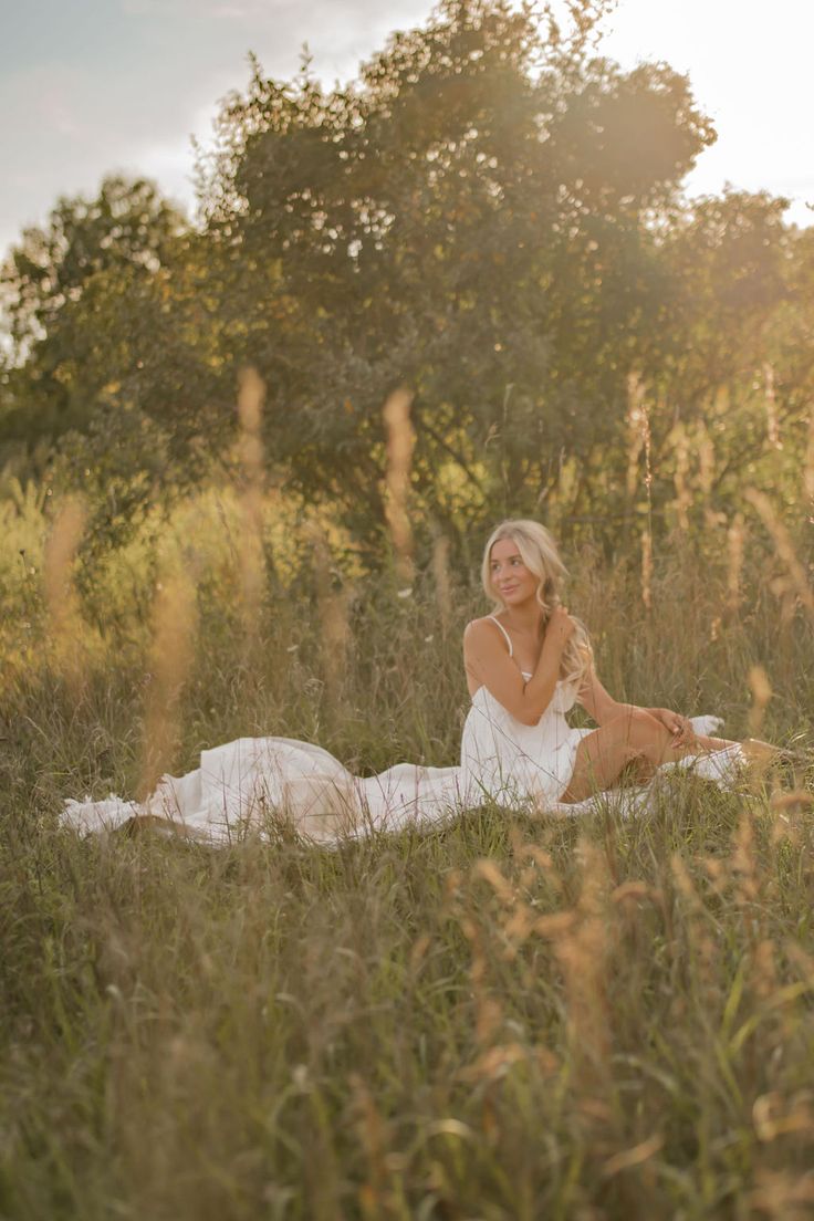 a woman sitting on the ground in tall grass