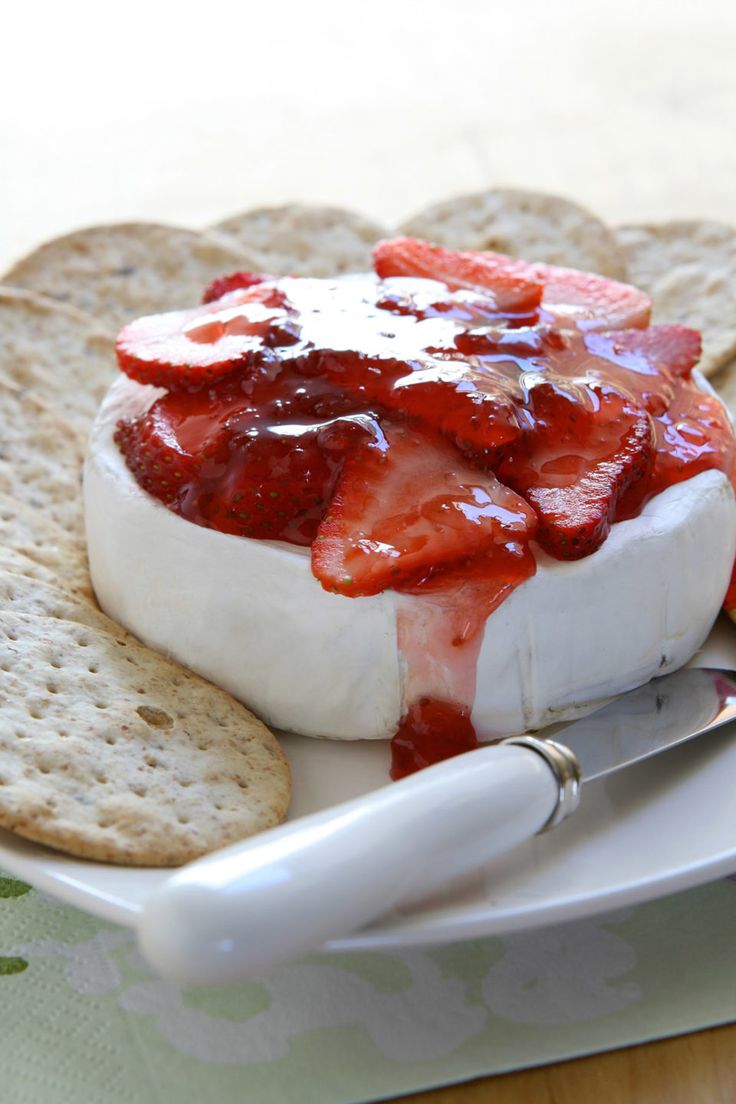 a plate topped with crackers and cheese covered in strawberries