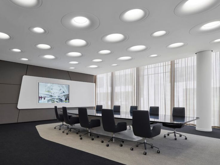 an empty conference room with black chairs and round lights on the ceiling, along with large windows