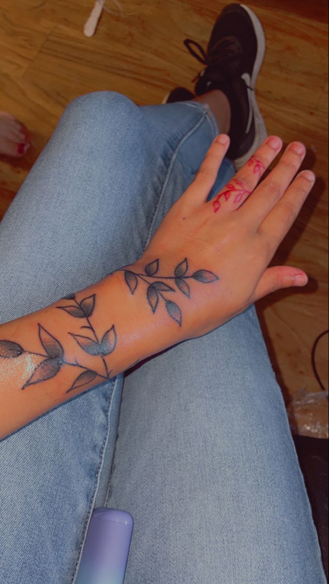 a woman's arm with tattoos on it and her hand resting on the floor