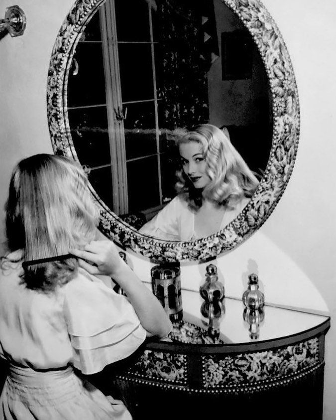 a woman is brushing her hair in front of a mirror while looking at herself in the mirror