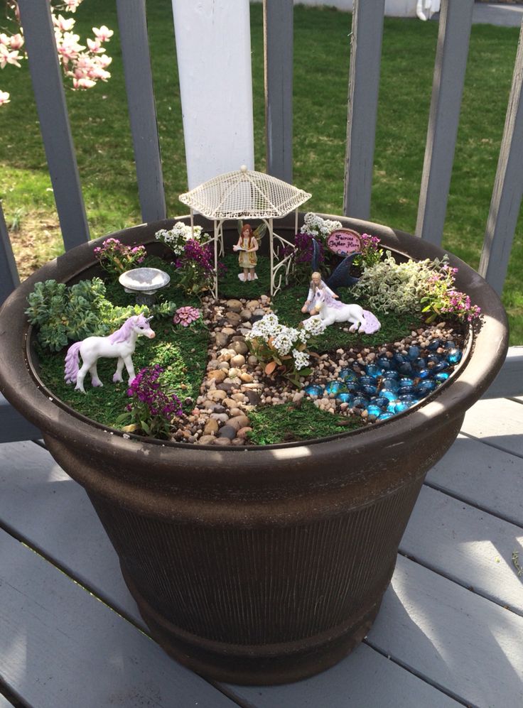 a potted planter filled with miniature animals and plants on top of a wooden deck