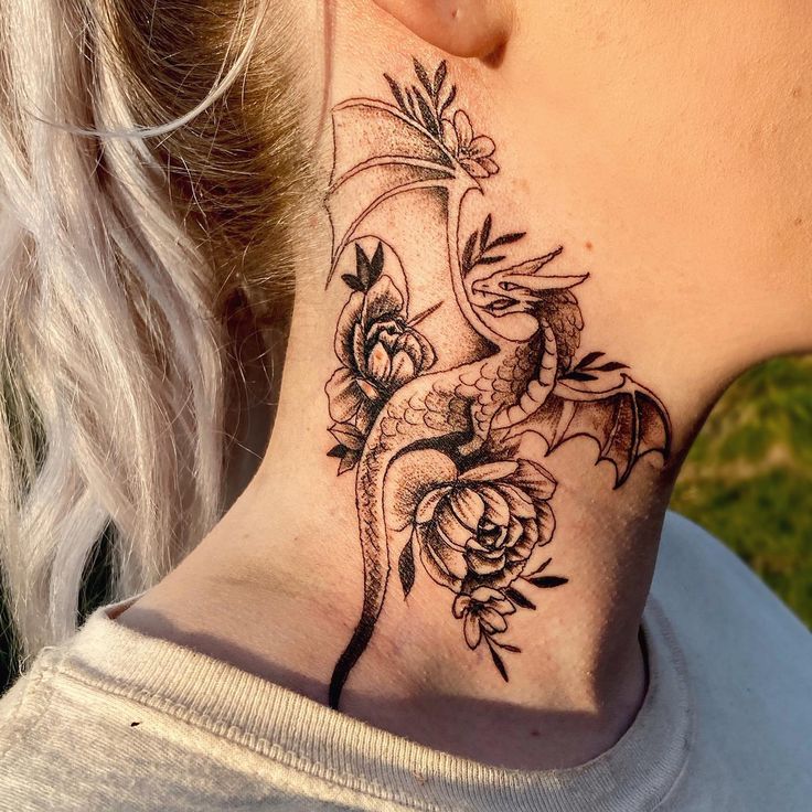 a woman's neck with a dragon and flowers tattoo on her left side ribcage