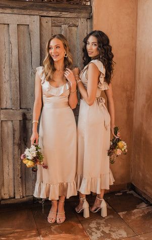 two beautiful women standing next to each other in front of a wooden door holding bouquets